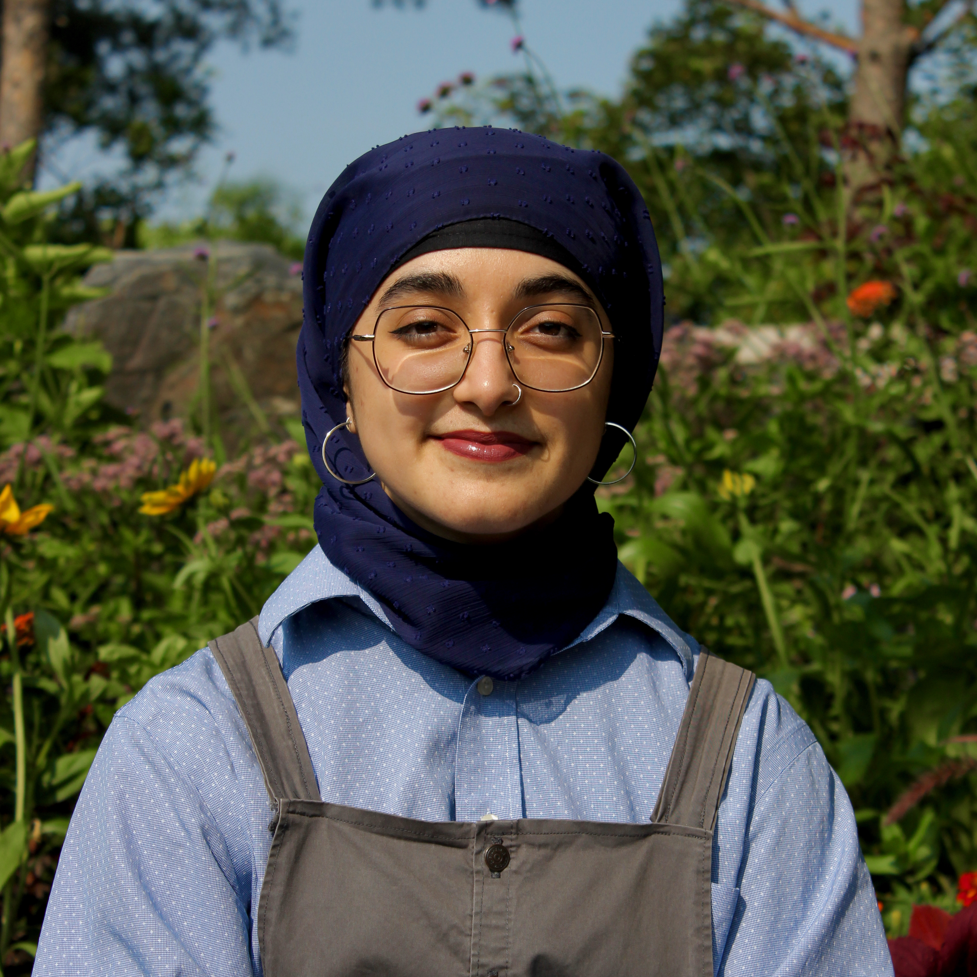 A picture of Ayesha Qadir (that's me!) from the bust up, sitting outside at midday in a park.